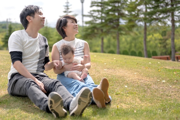 Eine Familie sitzt mit ihrem Baby im Gras