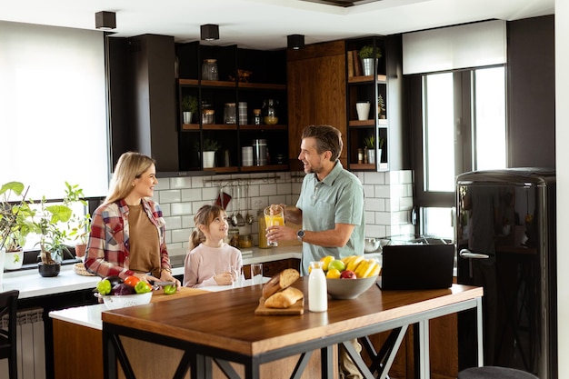 Eine Familie unterhält sich und bereitet Essen vor einer geschäftigen Küchenplatte, die mit frischen Zutaten und Kochgeräten gefüllt ist