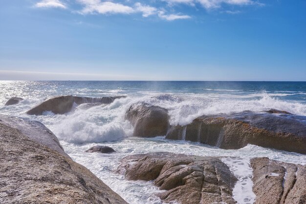 Eine felsige Küste und ein Blick auf das Meer mit Wellen blauer Himmel kopieren Raum und einen Horizont im Hintergrund in Camps Bay Kapstadt Südafrika Ruhiger ruhiger Strand und Naturkulisse