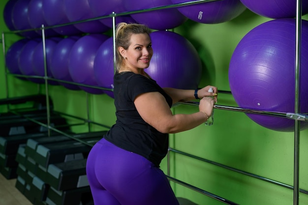 Eine fette Frau macht Aerobic und versucht, Gewicht zu verlieren, ein fettlebes Mädchen entspannt sich im Fitnessstudio mit Fitnessbällen.