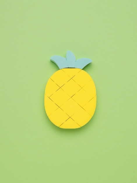 Eine Figur einer hellen reifen Ananas auf einem hellgrünen Hintergrund. Das Konzept der tropischen Früchte. Minimales Sommerkonzept.