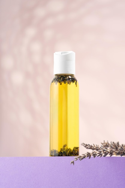 Eine Flasche ätherisches Lavendelöl Lavendelblüten auf einem lila Podium Kosmetisches ätherisches Öl für Körperbäder auf hellem Hintergrund Phytotherapie Aromatherapie Selbstpflege Ernährung trockener Haut