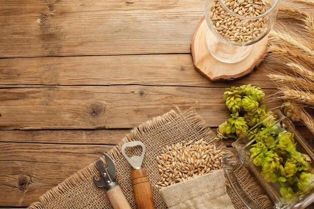 Eine Flasche Bier mit grünem Hopfen-Hafer-Weizen-Ährchen-Öffner und Gläser mit dunklem und hellem Bier auf schwarz zerkratzter Kreidetafel Draufsicht