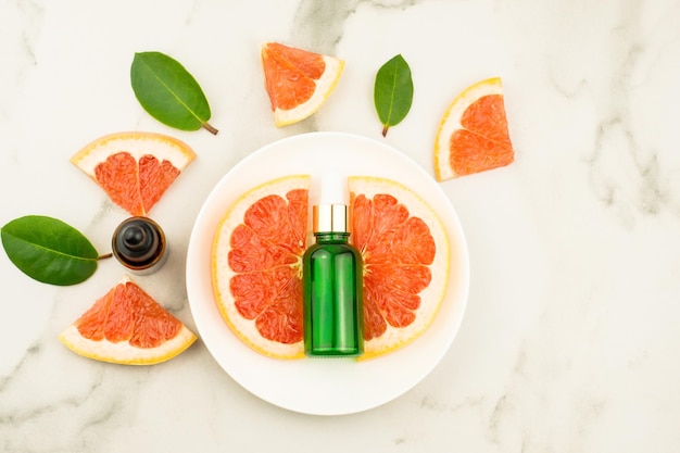 Eine Flasche essentieller Grapefruit auf einem weißen Teller und einem Marmortisch. natürliche Grapefruit, Vitamin C. Ansicht von oben.