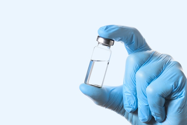 Eine Flasche Impfstoff zur Injektion in der Hand des Arztes auf hellblauem Hintergrund