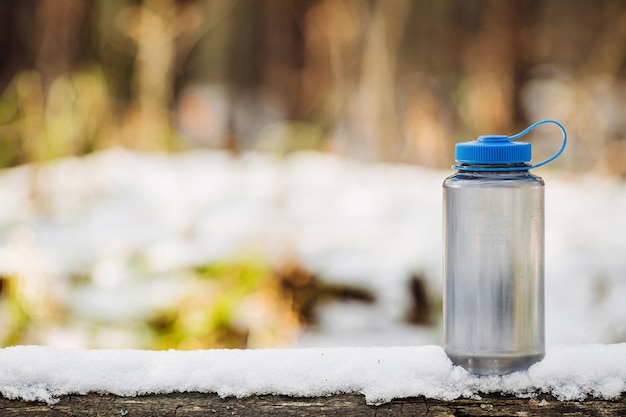 Eine Flasche kaltes Wasser auf Holz mit Winterszenenhintergrund