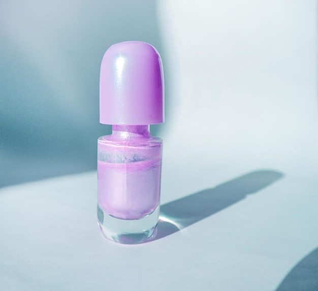 Eine Flasche lila Nagellack auf einer weißen Oberfläche mit Schatten ein modisches Schönheitskonzept
