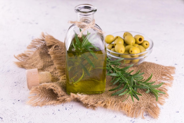 Eine Flasche Olivenöl neben einer Schale mit grünen Oliven