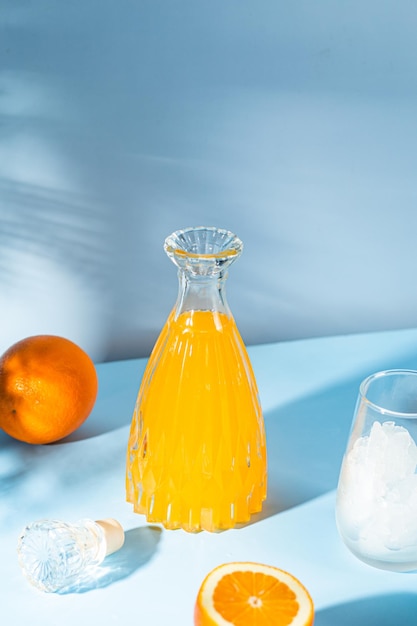 Eine Flasche Orangensaft und ein Glas Orangensaft auf blauem Hintergrund.