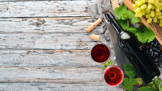 Eine Flasche Rotwein auf weißem Holzhintergrund Traube Freier Platz für Text Ansicht von oben