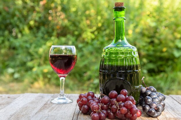 Eine Flasche Rotwein und eine Weintraube