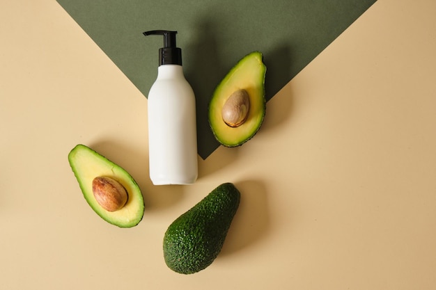 Eine Flasche Sahne mit Avocadoscheiben auf grünem Hintergrund Naturkosmetik-Konzept