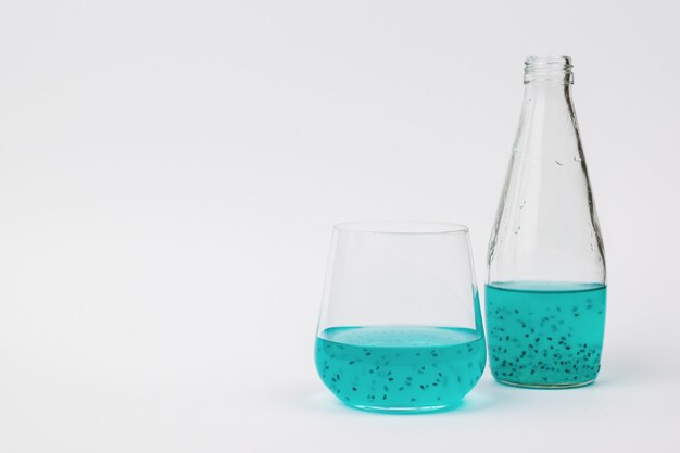Foto eine flasche und ein glas mit einem exotischen cocktail auf einer hellen oberfläche