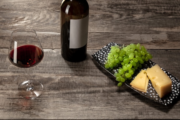 Eine Flasche und ein Glas Rotwein mit Früchten auf Holzhintergrund