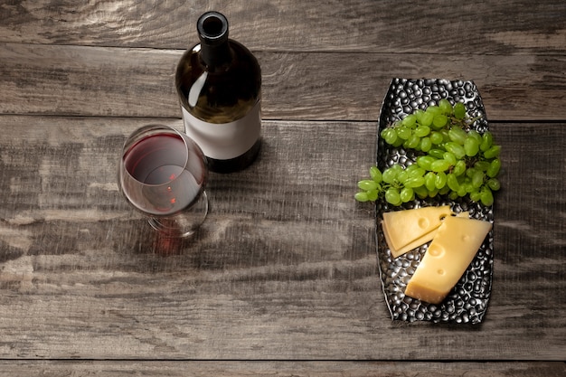 Eine Flasche und ein Glas Rotwein mit Früchten auf Holzhintergrund