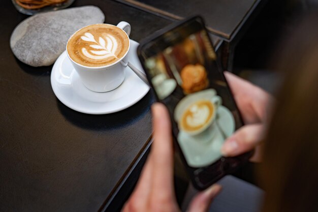 Foto eine food-bloggerin nimmt mit ihrem smartphone einen cappuccino-schuss