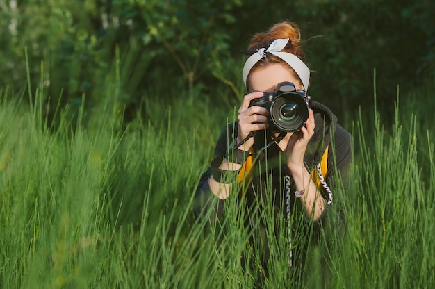 Foto eine fotografin hält eine professionelle foto-video-kamera in den händen. vor der kulisse wunderschöner grüner natur und wälder.