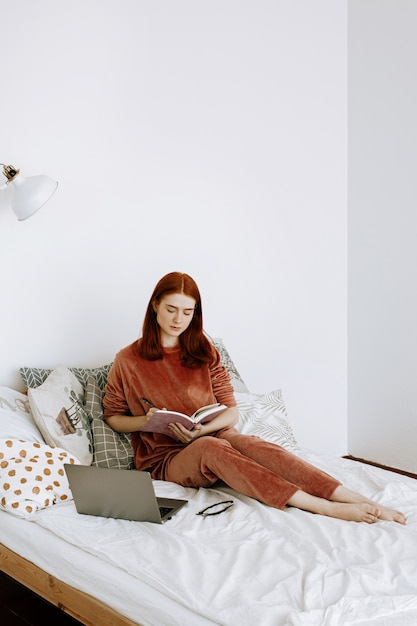 Eine Frau arbeitet zu Hause in ihrem Schlafzimmer an einem Laptop