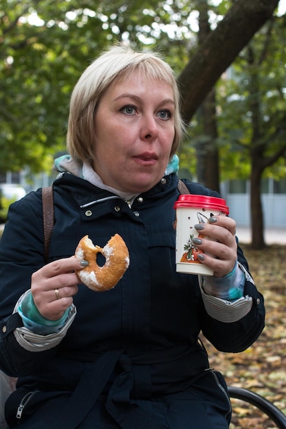 Eine Frau auf der Straße trinkt Kaffee mit Donuts Ein Spaziergang und ein leichter Snack