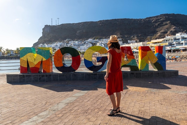 Eine Frau auf einem Touristenschild in der Küstenstadt Mogan im Süden von Gran Canaria, Spanien