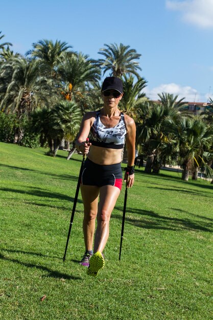 Eine Frau beim Nordic Walking im Park