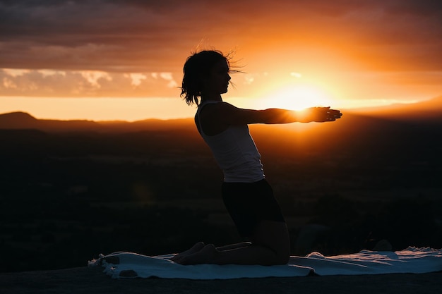 Eine Frau beim Yoga vor einem Sonnenuntergang