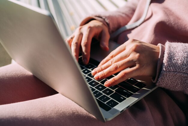 Eine Frau benutzt einen Laptop auf der Straße. Heimarbeit.