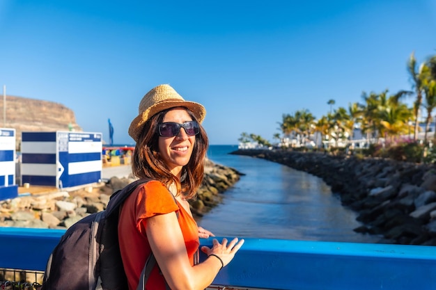 Eine Frau betrachtet den Hafen der touristischen Küstenstadt Mogan im Süden von Gran Canaria, Spanien