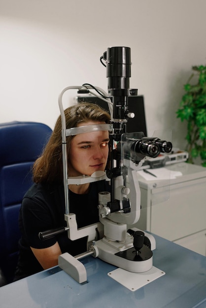 Eine Frau blickt durch ein Mikroskop auf eine Augenverletzung am Tisch