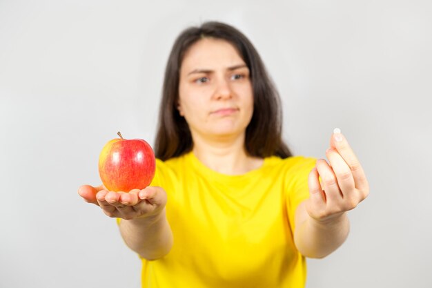 Eine Frau denkt, dass sie einen Apfel oder eine Pille mit Vitaminen wählen soll