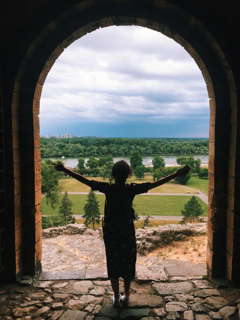 Foto eine frau, die an der bogentür steht, in voller länge von hinten