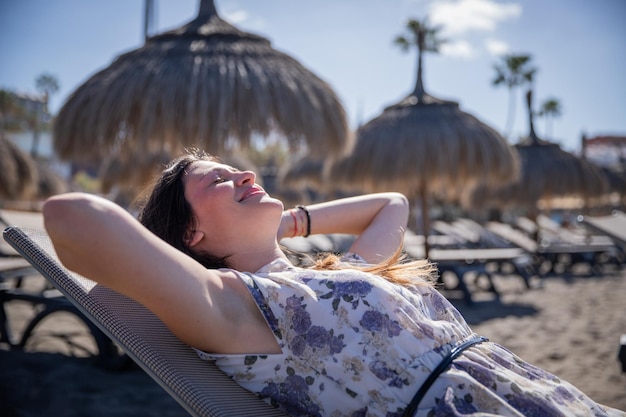 Eine Frau, die auf einer Sonnenliege am Strand liegt, ruht sich aus und genießt ihr sorgloses Urlaubskonzept