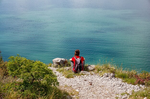 Eine Frau, die das adriatische Meer vom Karstrand nahe Triest, Italien betrachtet