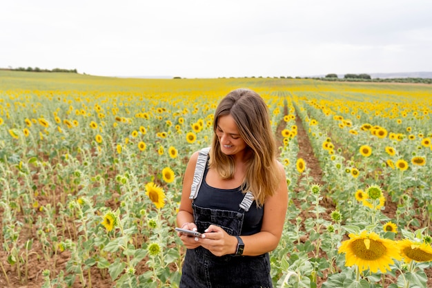 Eine Frau, die ein Handy unter Sonnenblumen benutzt.