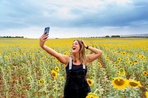 Eine Frau, die ein Handy unter Sonnenblumen benutzt.