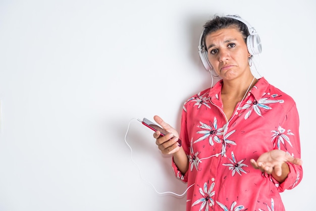 Eine Frau, die ein Hawaiihemd mit Blumendruck trägt, hält einen MP3-Player in der Hand und blickt in die Kamera.