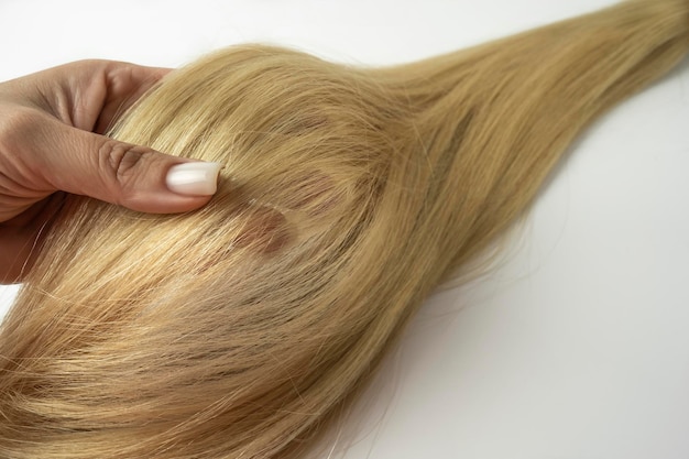 Eine Frau, die eine blonde Haarlage in ihrer Hand hält