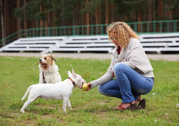 Eine Frau, die einem Hund einen Knochen füttert