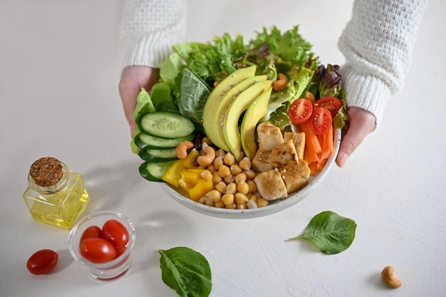 Eine Frau, die einen Teller mit leckerem, gesundem Salat mit gegrilltem Tofu-Diät-Food-Menü auf Pflanzenbasis hält