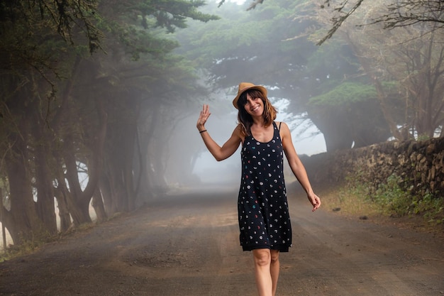 Eine Frau, die es genießt, durch neblige Bäume in Richtung des Wacholderwaldes auf den Kanarischen Inseln von El Hierro zu gehen