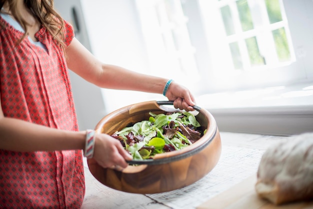 Eine Frau, die Essen zu einem Tisch trägt und sich auf ein Familienessen vorbereitet