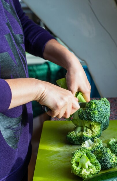 Eine Frau, die frischen Brokkoli schneidet. Konzept für gesunde Ernährung.