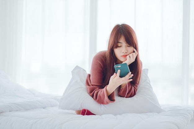 Eine Frau, die im Bett im Haus telefoniert