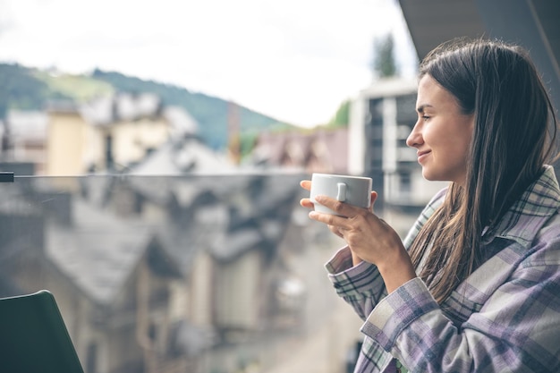 Eine Frau, die morgens auf dem Balkon Kaffee trinkt