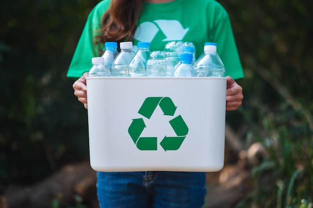 Eine Frau, die Müll sammelt und einen Papierkorb mit Plastikflaschen im Freien hält