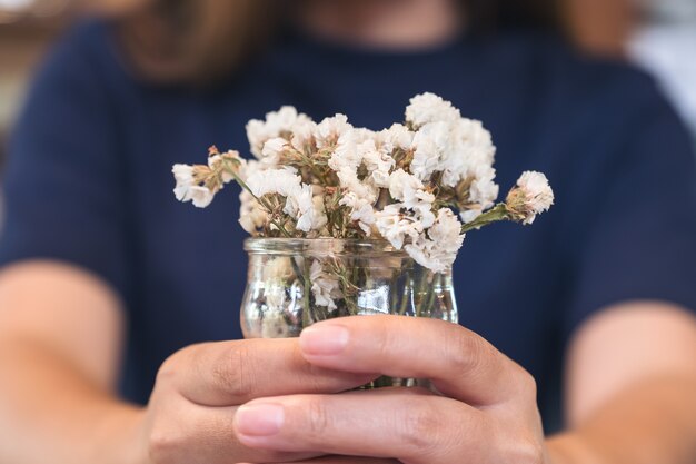 Eine Frau, die nach innen einen Vase mit weißen Blumen hält