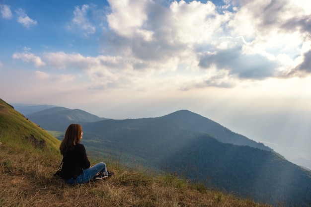 Eine Frau, die Sonnenuntergang mit Blick auf die Berge am Abend sitzt und beobachtet