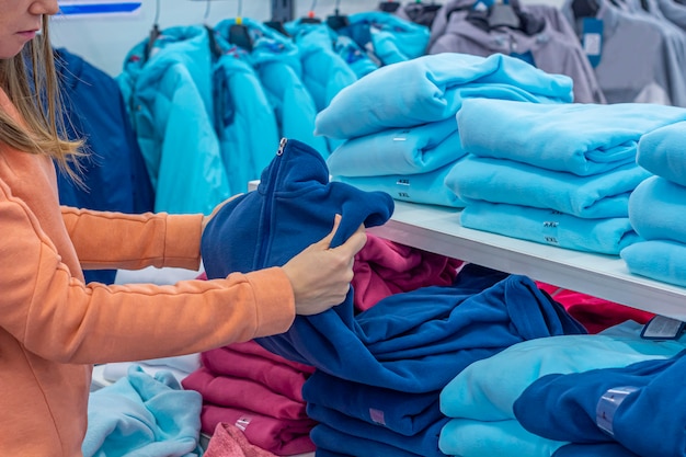 Eine Frau, die Sweatshirt oder Hoodie in einem modernen Sportgeschäft wählt