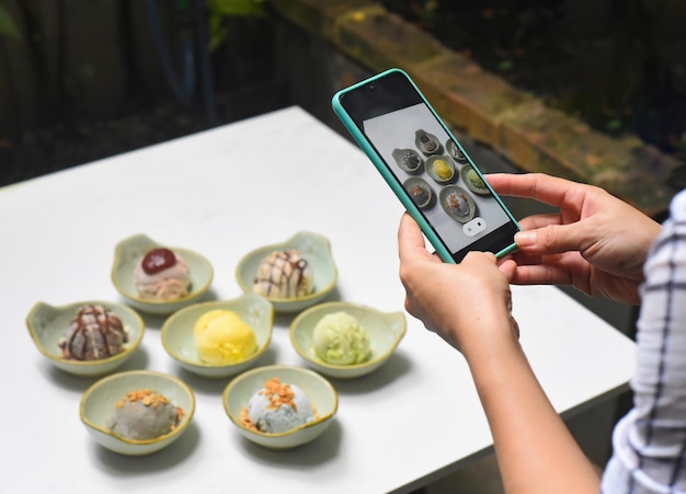 Eine Frau, die viele Eiscreme auf einem weißen Tisch fotografiert