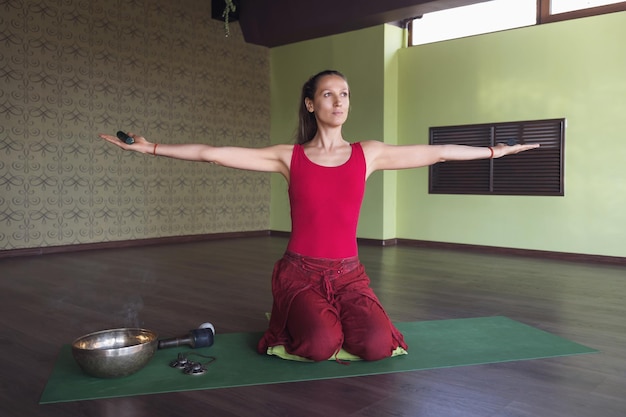 Eine Frau, die Yoga praktiziert und mit Stöcken in den Händen und verschiedenen Räucherstäbchen meditiert